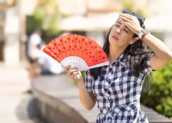 A woman fans herself in the heat.
