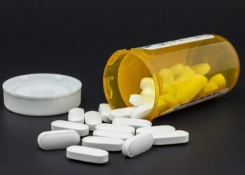 Bottle of spilled pills on black background