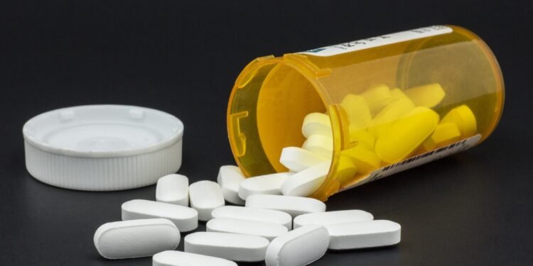 Bottle of spilled pills on black background