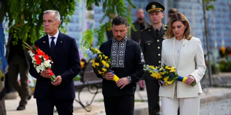 Canada's Prime Minister Mark Carney joins Ukrainian President Volodymyr Zelensky and his wife, Olena Zelenska, as they lay wreaths at the memorial wall in Kyiv