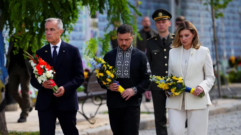 Canada's Prime Minister Mark Carney joins Ukrainian President Volodymyr Zelensky and his wife, Olena Zelenska, as they lay wreaths at the memorial wall in Kyiv