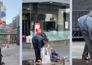 man washing clothes under Toronto fountain
