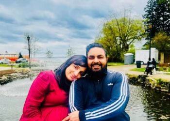 a man and woman sitting next to a pond