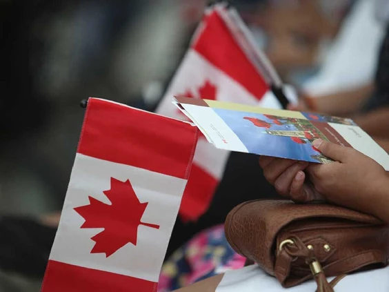 People hold Canadian flags at an citizenship ceremony in Toronto