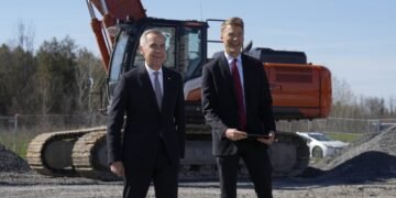 Prime Minister Mark Carney waits with Housing and Infrastructure Minister Gregor Robertson before speaking at an event in Ottawa