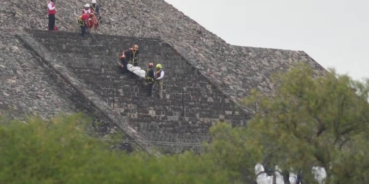 Forensic workers carry the body of a victim down a pyramid after authorities said a gunman opened fire