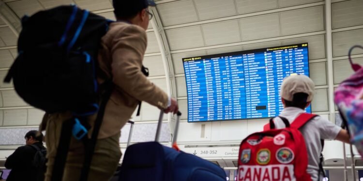 Travellers look at departures by the WestJet gate as the airline's flight attendants strike outside at Pearson International Airport in Toronto, on Sunday