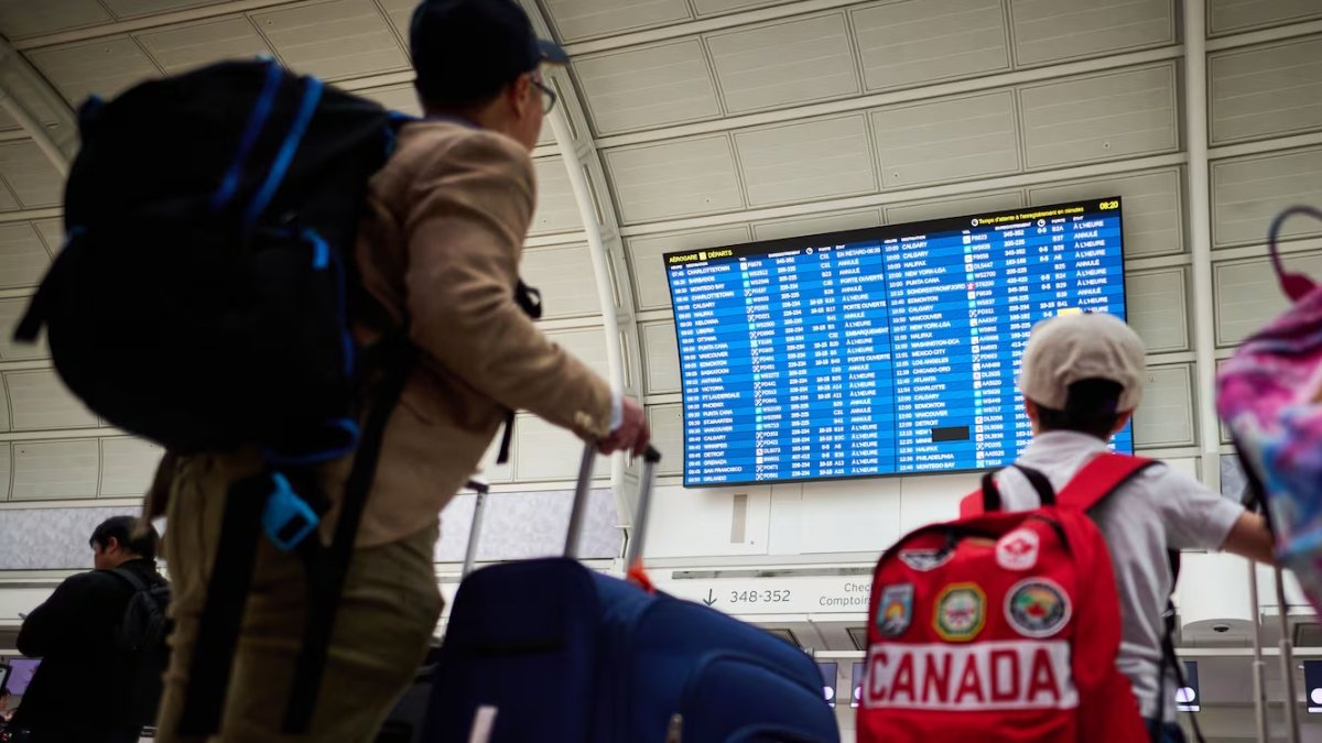 Travellers look at departures by the WestJet gate as the airline's flight attendants strike outside at Pearson International Airport in Toronto, on Sunday
