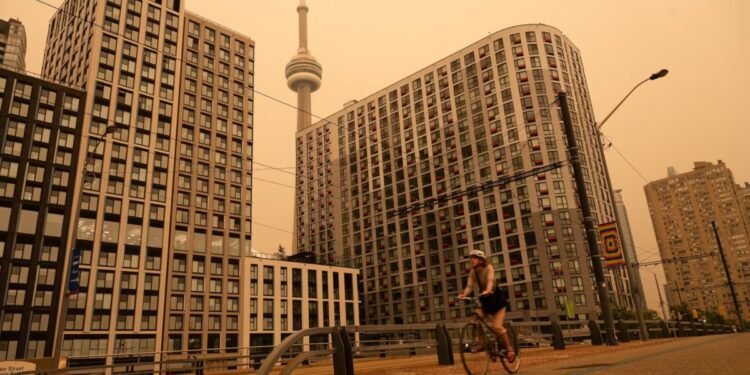 A woman bikes along the waterfront in Toronto as wildfire smoke fills the city,