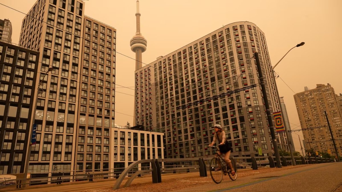 A woman bikes along the waterfront in Toronto as wildfire smoke fills the city,