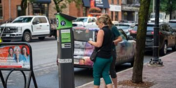 Two people pay for parking in Ottawa in July. Mayoral candidate Alex Lawson has pledged to eliminate paid on-street parking if he's elected