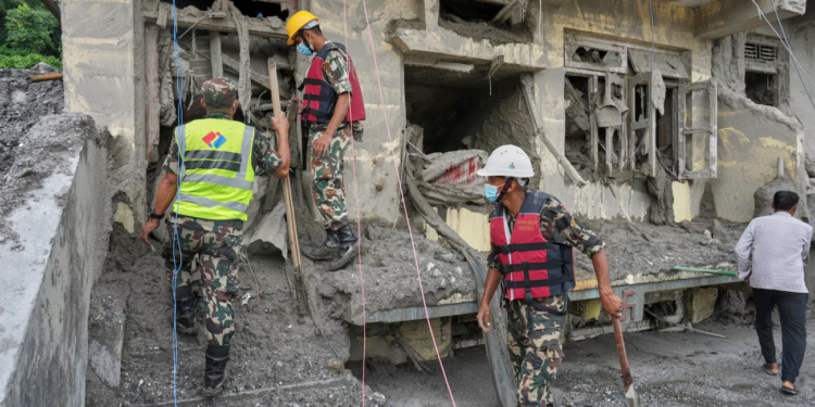 Rescuers inspect a residential building damaged in the aftermath of the flash floods in Nepal's Nuwakot district,