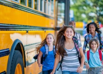 A group of children are running from the bus to class.