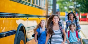 A group of children are running from the bus to class.