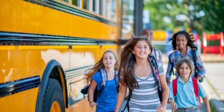A group of children are running from the bus to class.